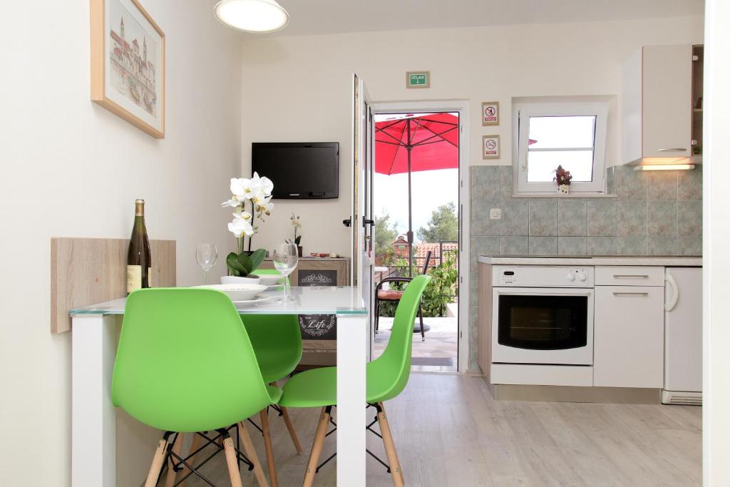 une cuisine avec une table et des chaises vertes dans l'établissement Apartments Viki, à Trogir