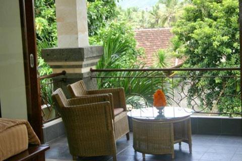 a patio with chairs and a table and a balcony at Puri Pondok Dawa Villa in Kusamba