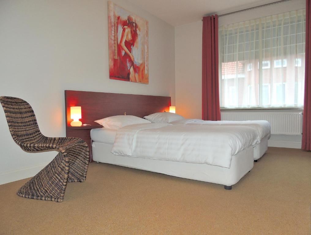 a bedroom with a white bed and a chair at Hotel Mieke Pap in Poppel