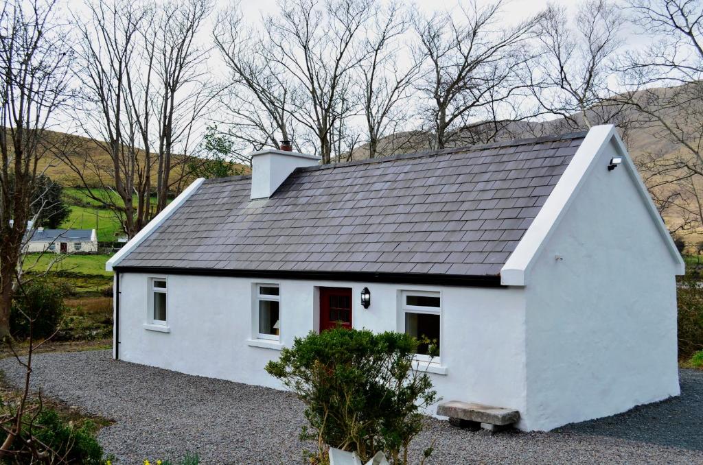 una pequeña casa blanca con techo negro en Cottage 194 - Leenane, en Leenaun