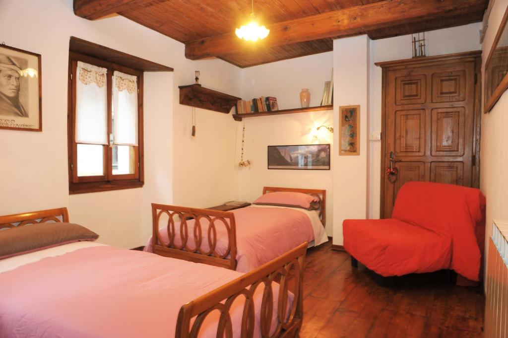 a bedroom with two beds and a chair at Tana del Paradiso in Baceno