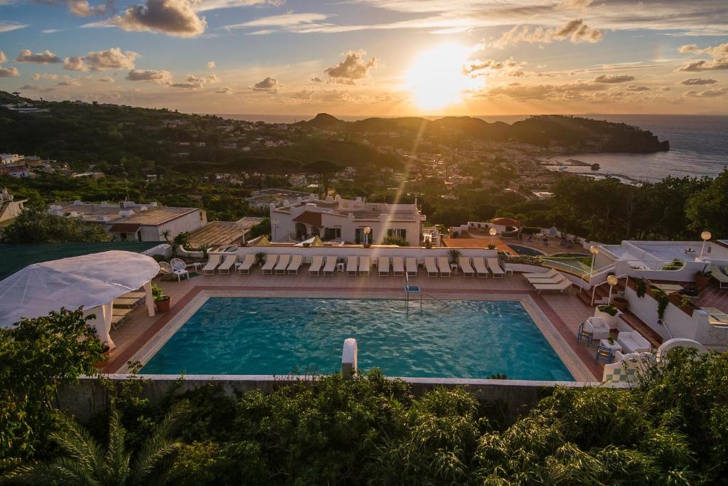 a large swimming pool with a sunset in the background at Paradise Relais Villa Janto' in Ischia