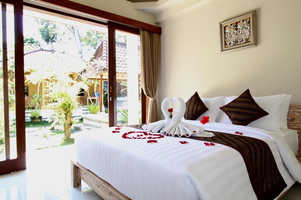 a bedroom with a white bed with red flowers on it at With Love Bali in Gianyar