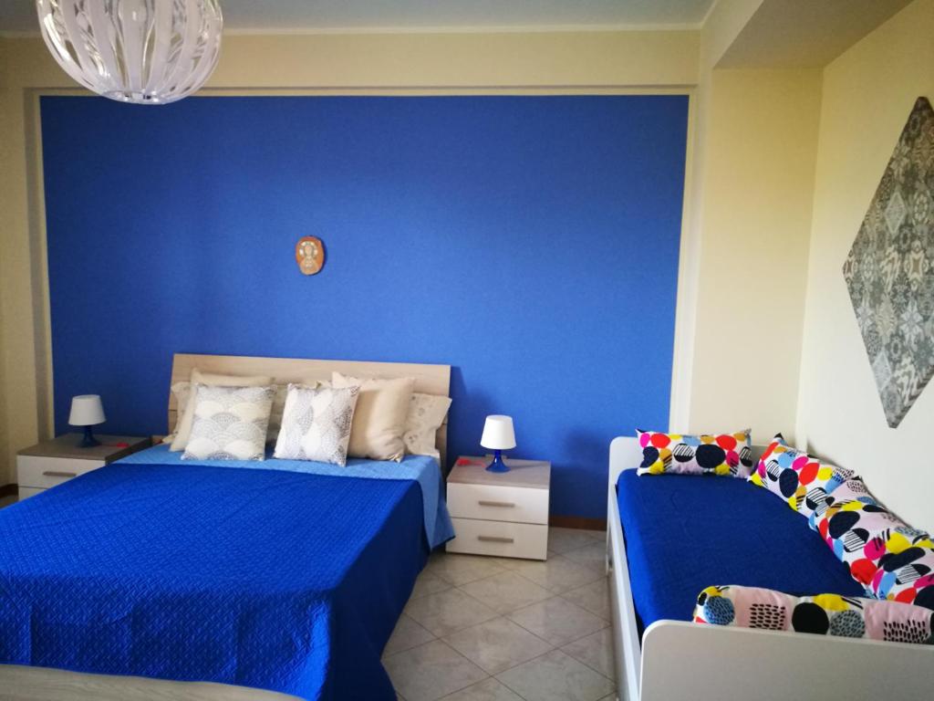 ein blaues Schlafzimmer mit 2 Betten und einer blauen Wand in der Unterkunft New Panoramic Apartment in Noto