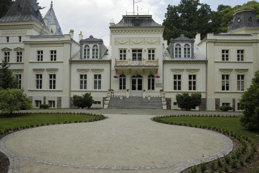 a large white house with a circular driveway at Pałac w Nosowie in Nosowo