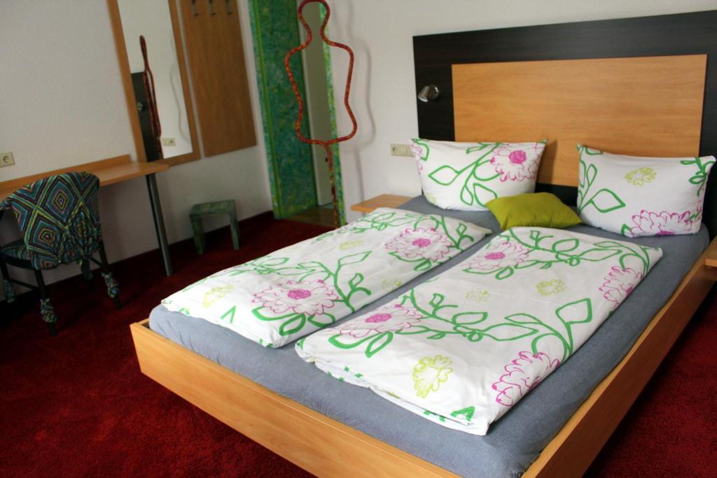 a bed with a wooden headboard and pillows on it at Donau Pension in Tuttlingen