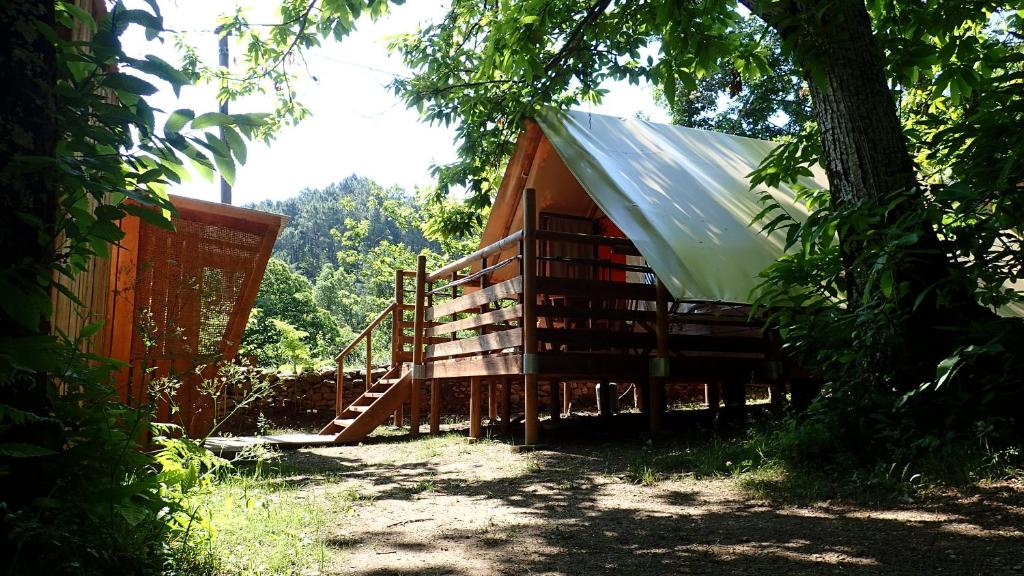 a house with a metal roof and stairs next to a tree at Camping La Châtaigneraie in Gravières