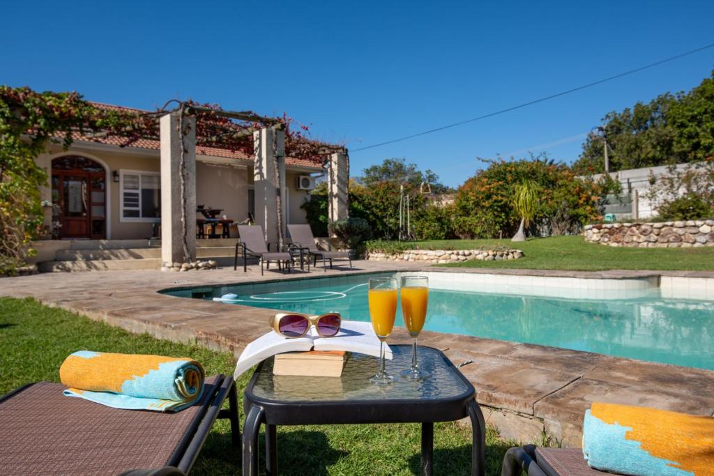 a table with two glasses of orange juice next to a pool at African Tulip Guesthouse in Tulbagh