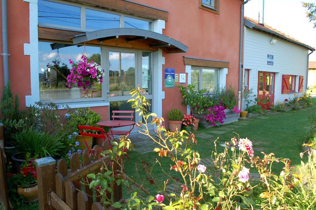 um jardim fora de uma casa com uma mesa e flores em B&B La Maison Des Collines Autour Chambres d'hôtes em La Chapelle