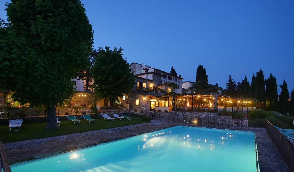 a swimming pool in front of a house at night at Relais Vignale & Spa in Radda in Chianti
