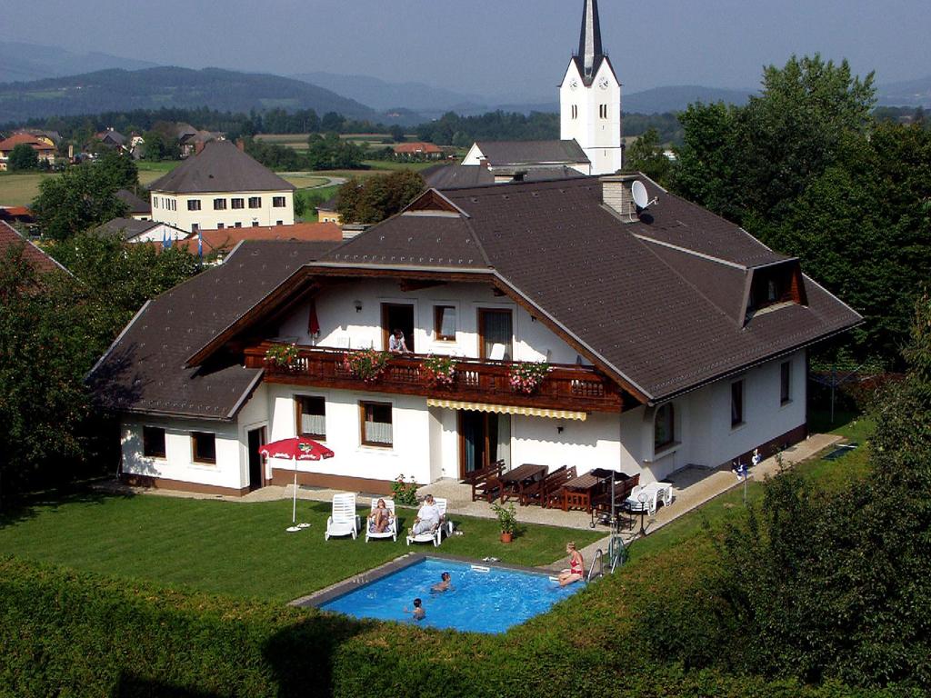 a house with a swimming pool and a church at Ferienwohnungen Schneider in Sankt Kanzian