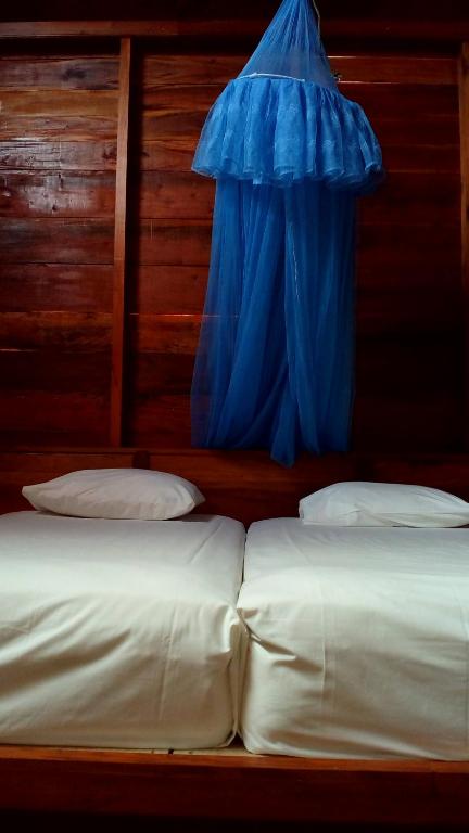 two beds in a room with a blue tarp over them at Dolin Cottage in Hilibotodane