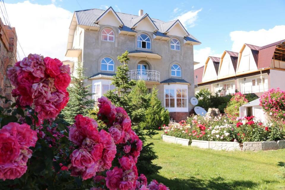 een groot huis met roze bloemen ervoor bij Гостевой дом "Ысык-Куль - Светлана" in Cholpon-Ata