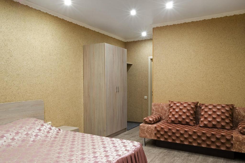 a bedroom with a bed and a cabinet and a chair at Guest House on Partizanskaya in Barnaul