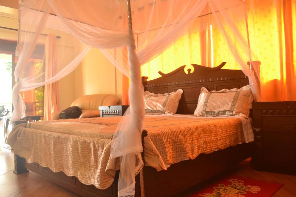 een slaapkamer met een groot bed met een baldakijn bij The Palms Beach Hotel in Entebbe