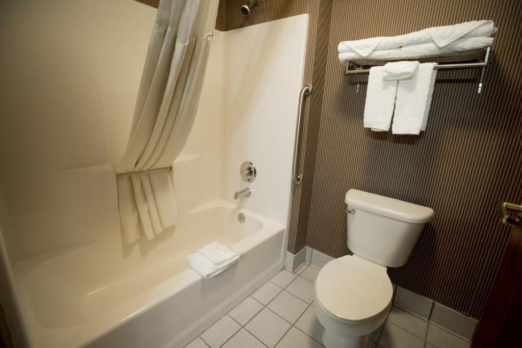a white toilet sitting next to a shower in a bathroom at Portland Suites Airport East in Portland
