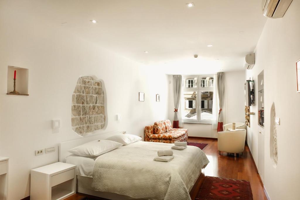 a white bedroom with a bed and a chair at Old Square Studio Apartment in Split