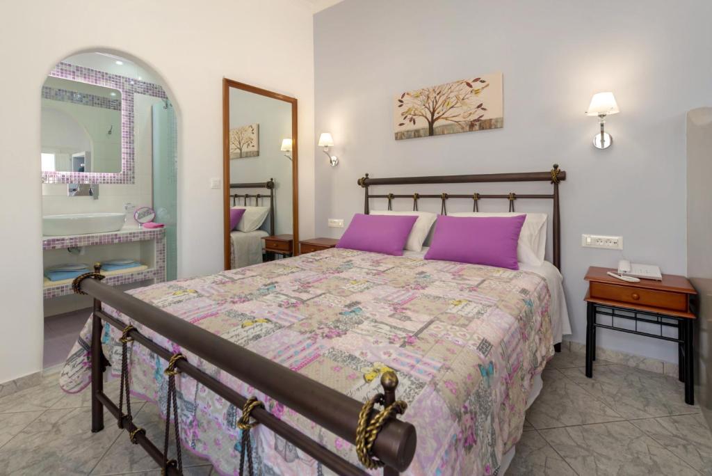 a bedroom with a bed with purple pillows and a mirror at Akis Hotel in Kamari