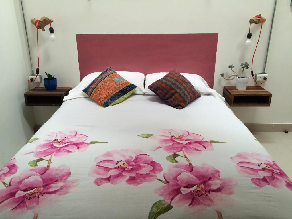 uma cama com flores cor-de-rosa com duas almofadas em Loft Alpaca em Iquique