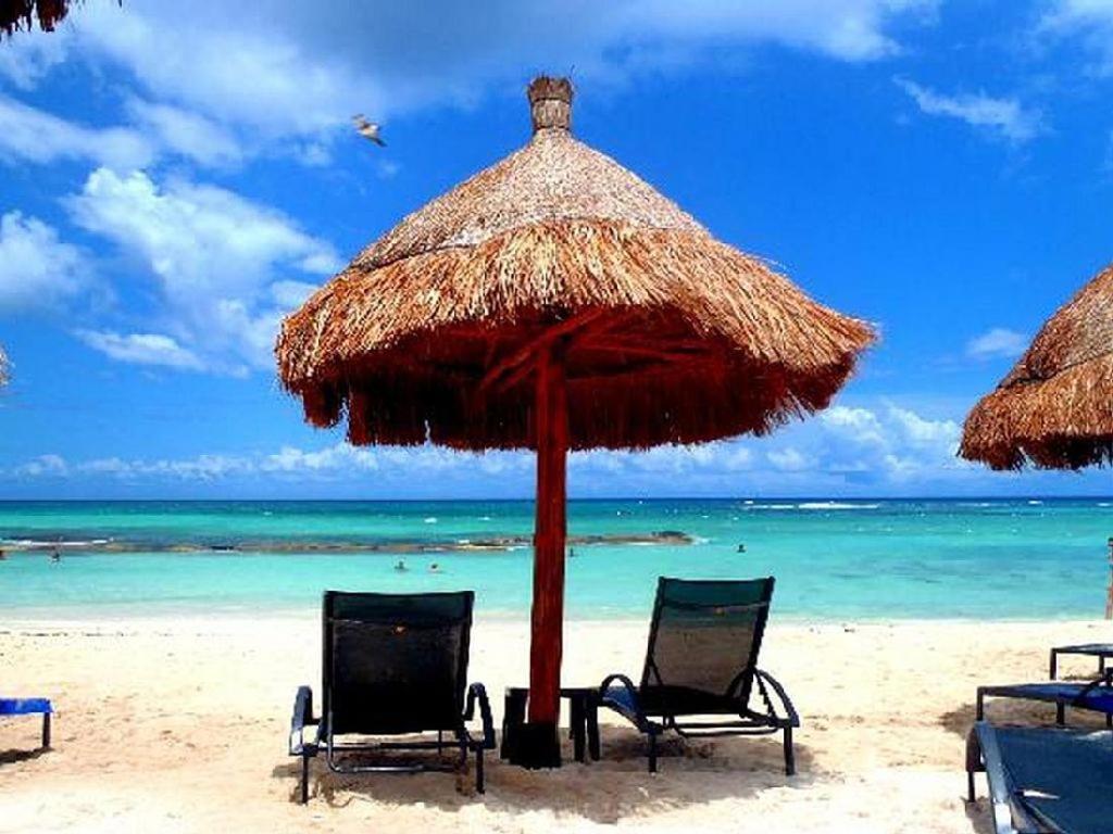 a beach with two chairs and an umbrella and the ocean at TAO Garden Luxury Condo in Akumal