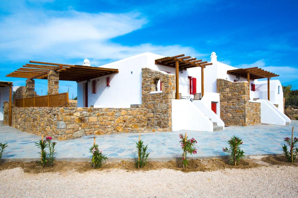 uma casa na praia com uma parede de pedra em Myconian Brothers em Ano Mera