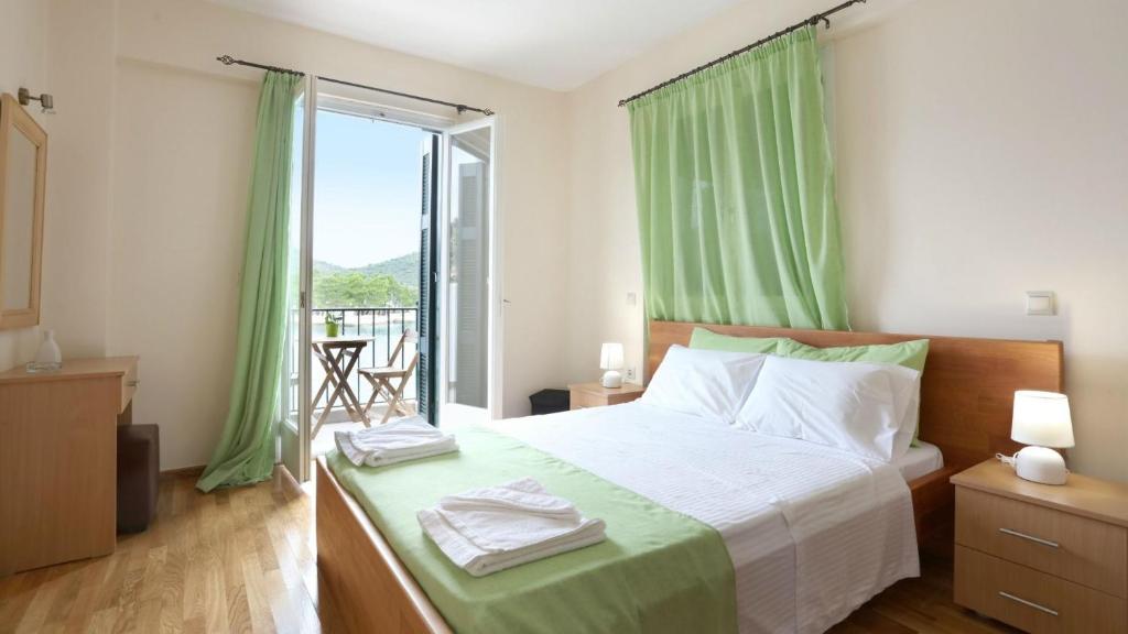 a bedroom with a bed with green curtains and a balcony at Lazaretto Palace in Vathi