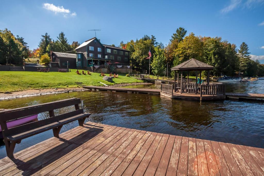 un banco sentado en un muelle junto a un cuerpo de agua en The Big Moose Inn, en Big Moose