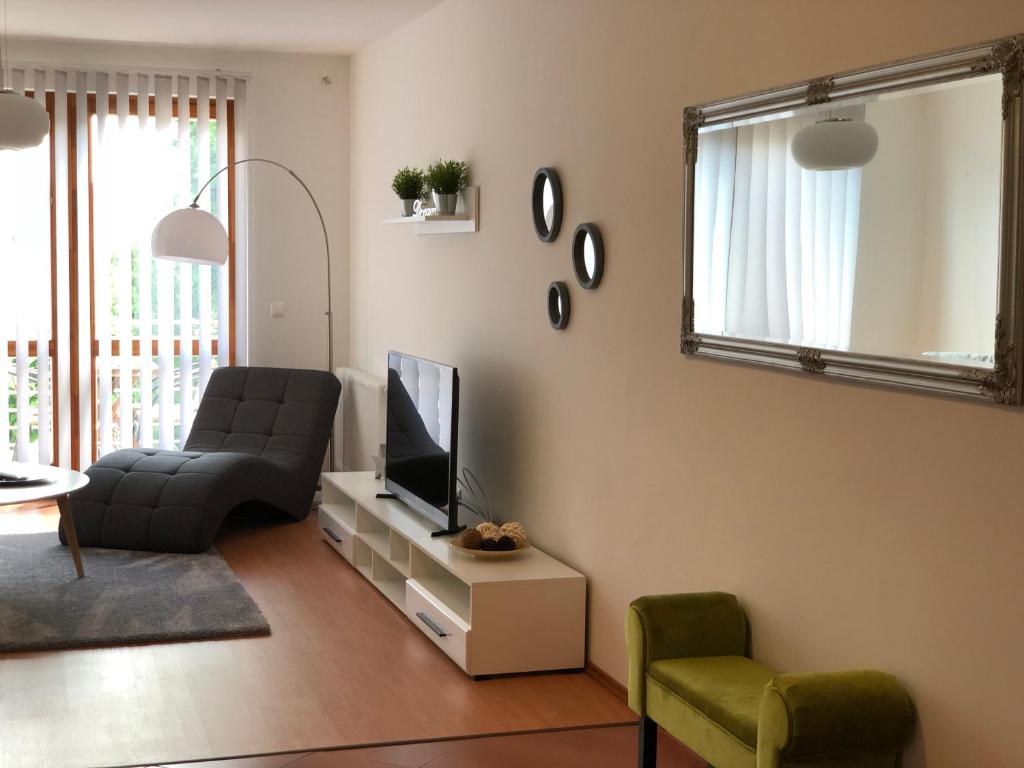 a living room with a couch and a television at Nexus Apartmenthotel in Hévíz