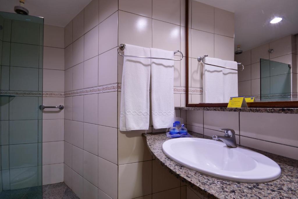 a bathroom with a sink and a mirror at Littoral Hotel in João Pessoa