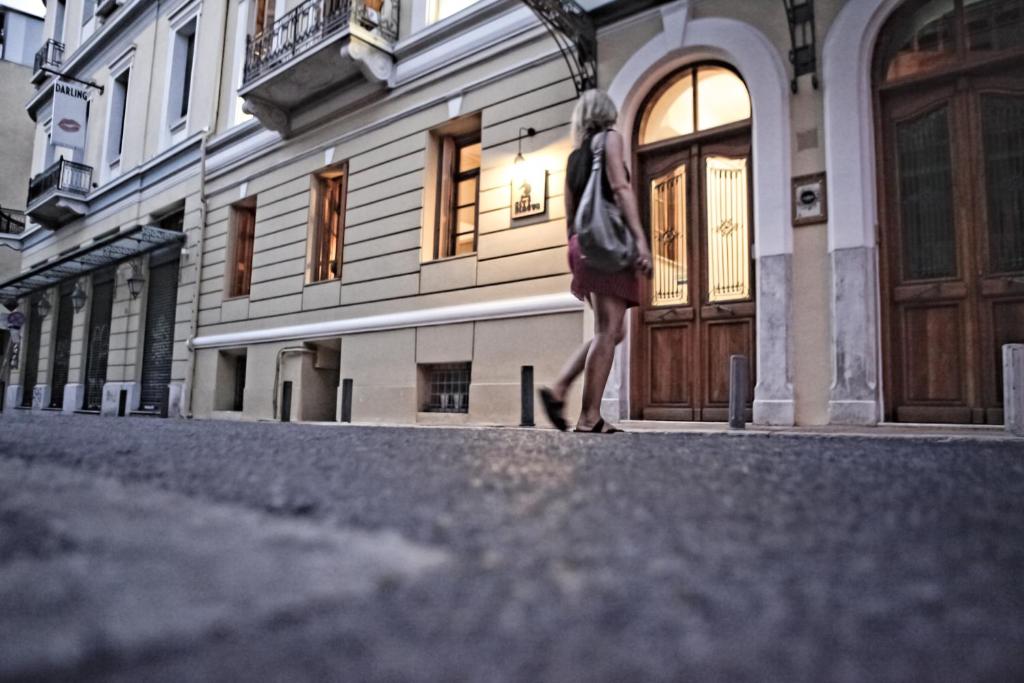 une femme marchant dans une rue devant un bâtiment dans l'établissement City Circus Athens, à Athènes