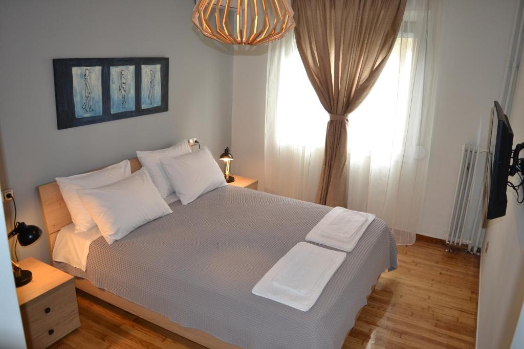 een slaapkamer met een bed met witte kussens en een raam bij Leon Cozy Apartment in Athene