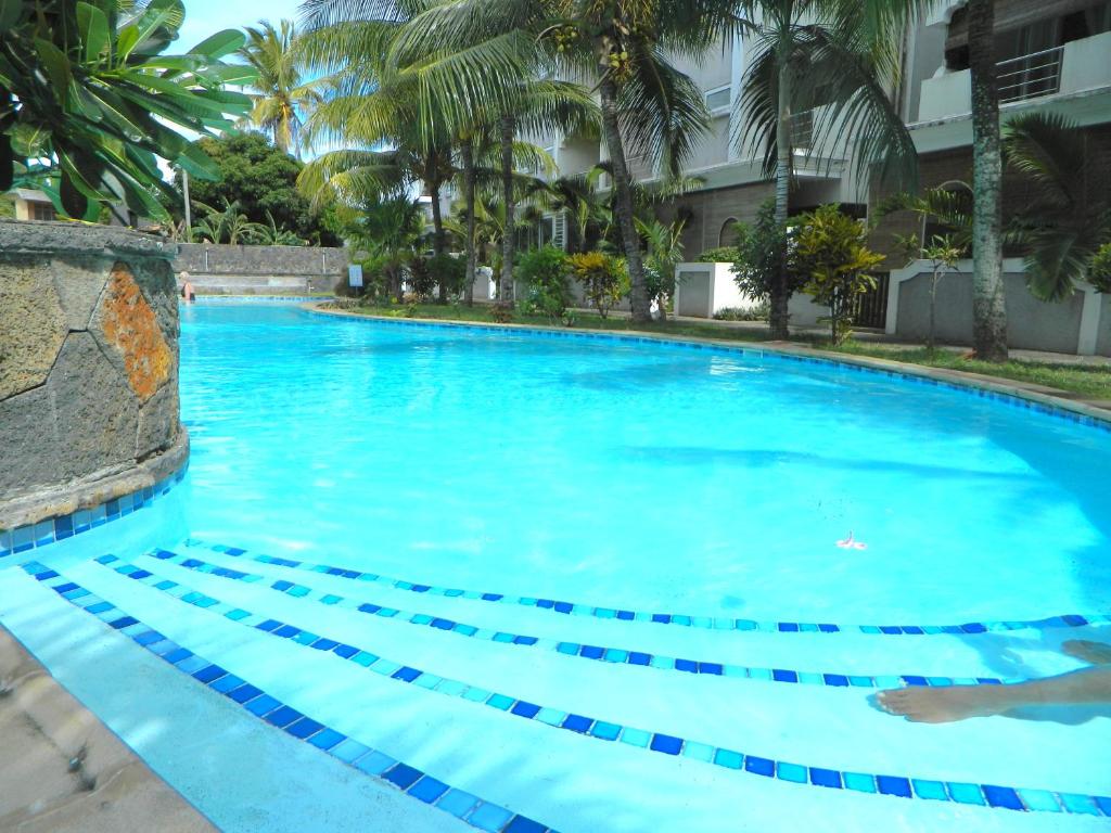 een groot blauw zwembad met palmbomen bij ARIEL BEACH VILLA* in Grand Baie