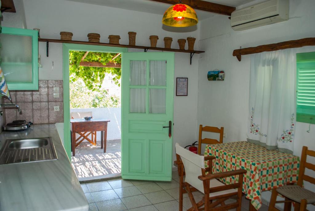 kuchnia z zielonymi drzwiami i stołem w obiekcie PATMOS Mathios Studios- apartments w mieście Patmos
