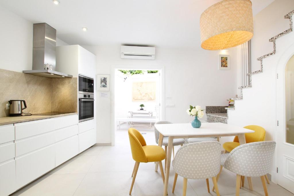 a kitchen with white cabinets and a table and chairs at Pollenca Townhouse in Pollença