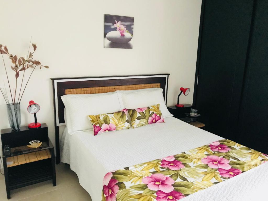 Un dormitorio con una cama con flores. en Hotel Meson de las Flores, en Armenia