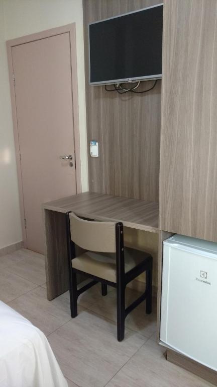 a desk with a chair and a television on a wall at Catalao Palace Hotel in Catalão