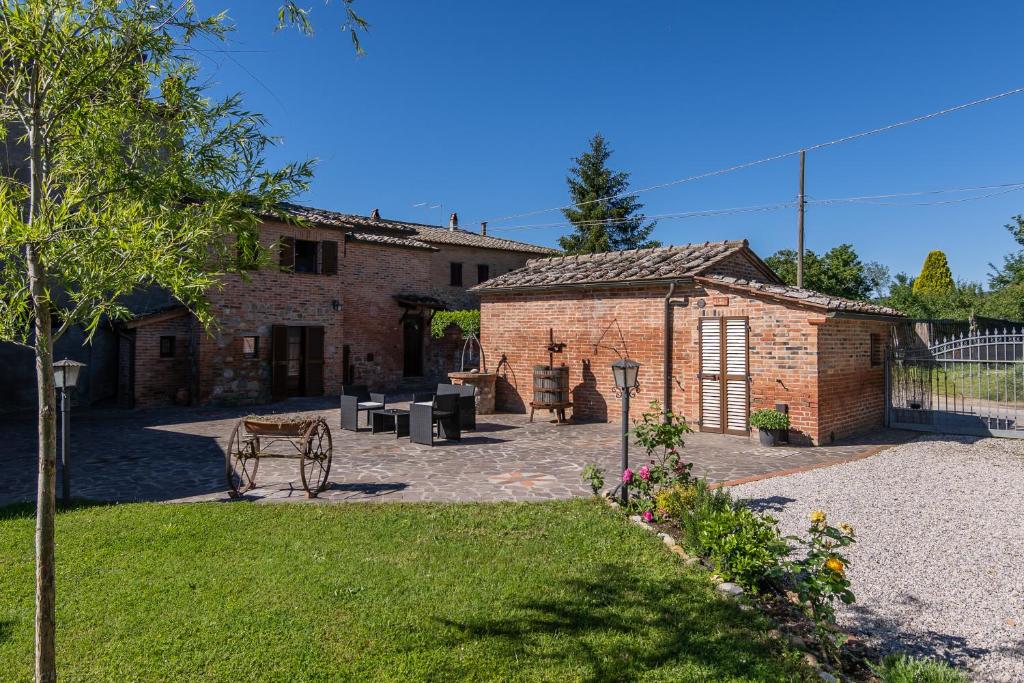 a brick building with a patio in a yard at Borgo Terrosi in Sinalunga