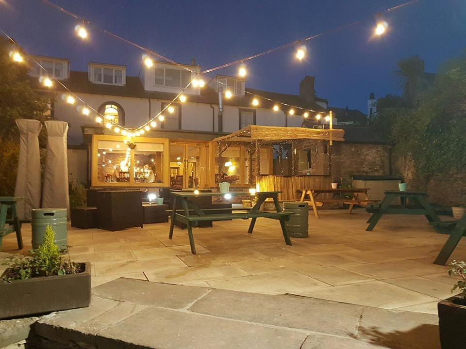 a patio at night with lights on a house at Queens Hotel in St Bees