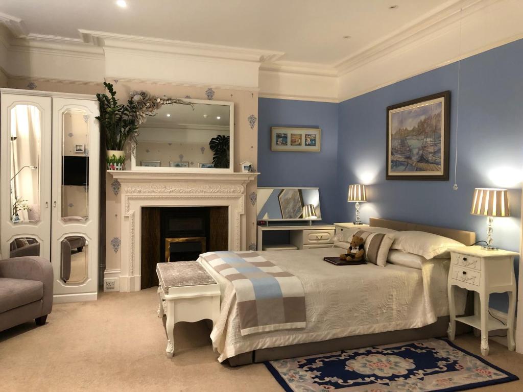 a blue bedroom with a bed and a fireplace at Arun Sands Rooms in Littlehampton