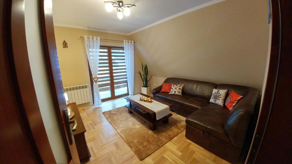 a living room with a leather couch and a table at Apartament Sokola Skała in Falsztyn