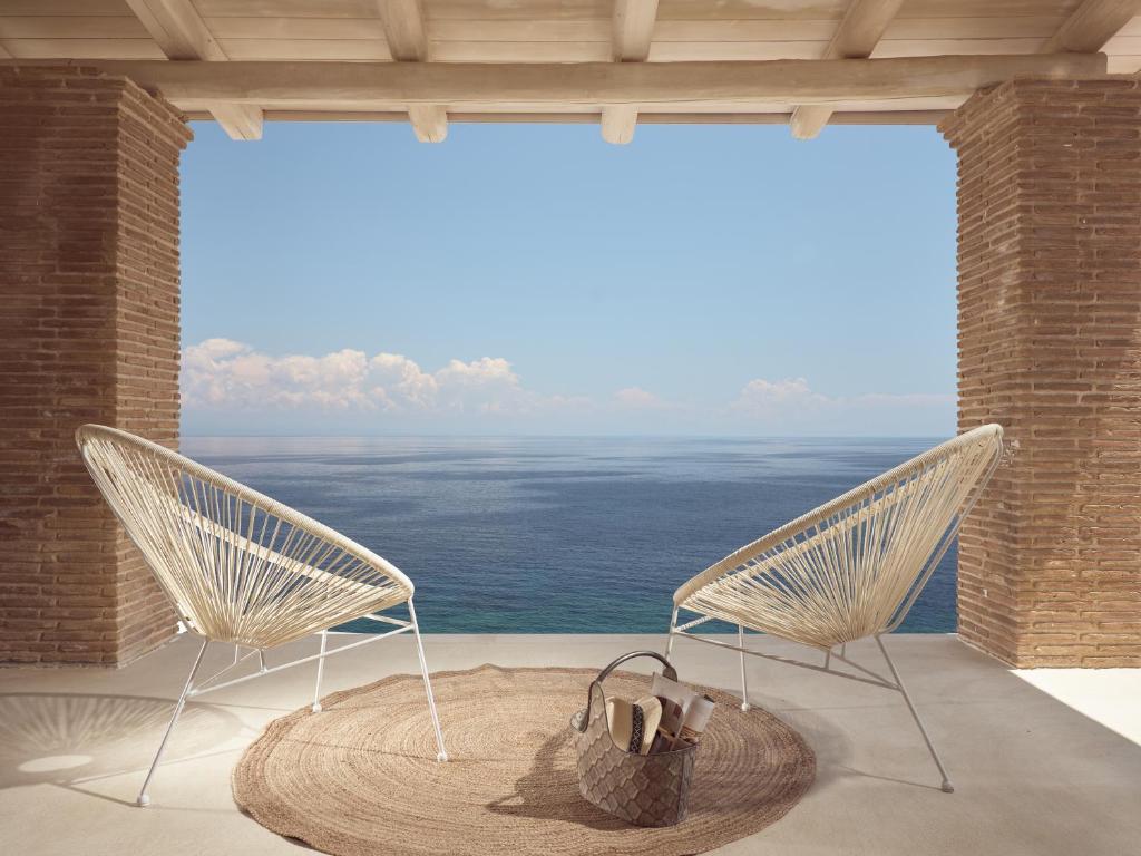 two chairs on a balcony with a view of the ocean at Arismari Luxury Villas in Vasilikos