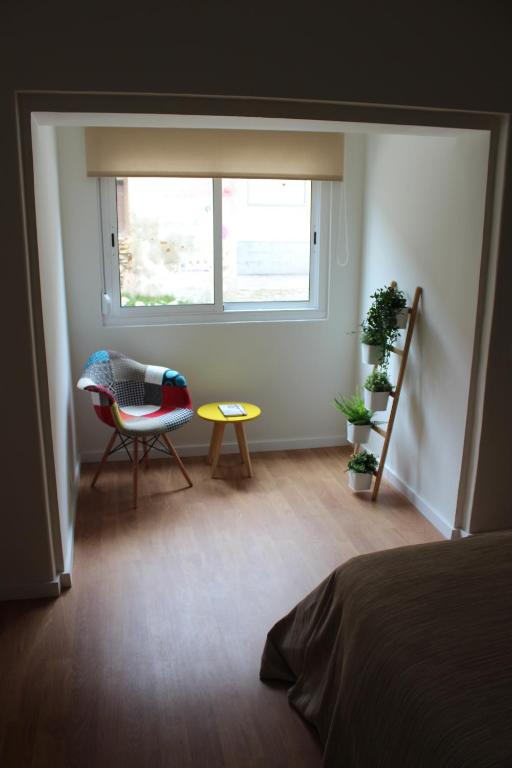a bedroom with a bed and a chair and a window at Casa da Azarujinha in Estoril