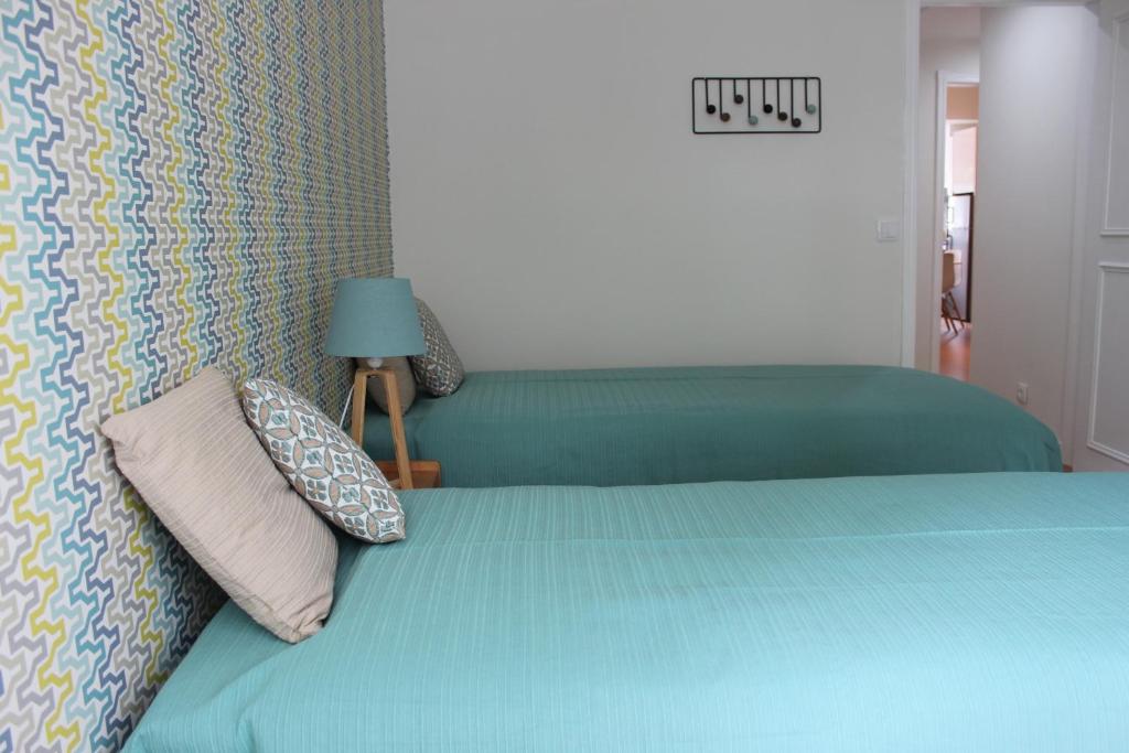 a bedroom with a bed with blue sheets and pillows at Casa da Azarujinha in Estoril