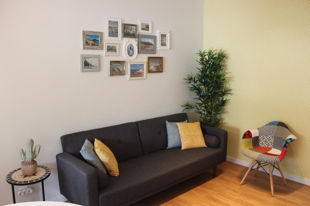 a black couch in a living room with pictures on the wall at Casa da Azarujinha in Estoril