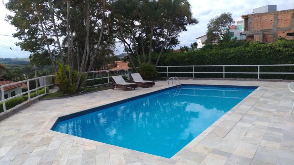 a blue swimming pool with two chairs and a fence at Casa em Escarpas do Lago in Capitólio