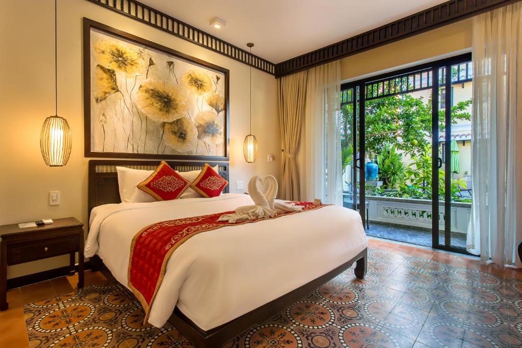 a bedroom with a large bed and a large window at Hoi An Field Boutique Resort & Spa in Hoi An