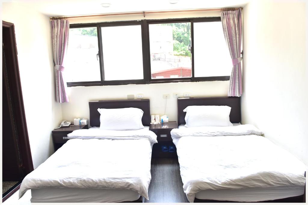 two beds in a room with two windows at Lian-Yuan Homestay No. 1 in Nangan