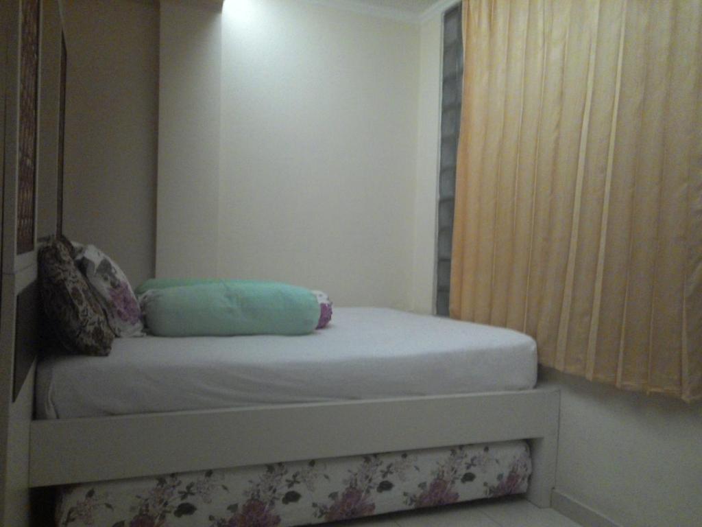 un piccolo letto in una camera con finestra di Kantos Guest House a Giacarta