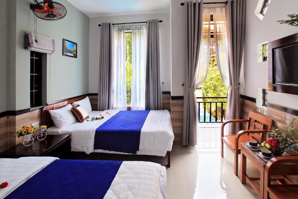 um quarto de hotel com duas camas e uma janela em An Thinh Homestay em Hoi An