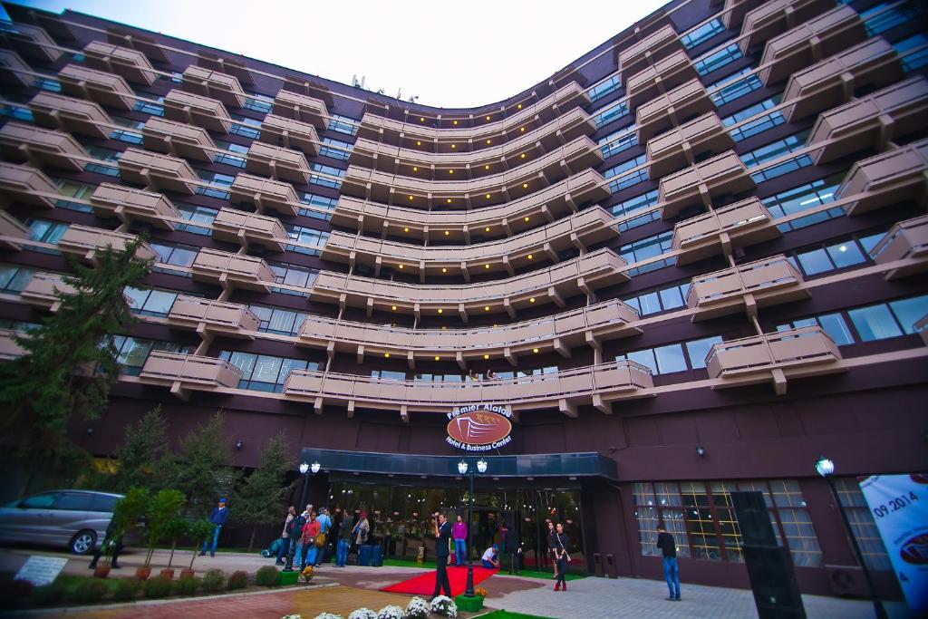 un gran edificio con gente parada fuera de él en Premier Alatau Hotel, en Almaty